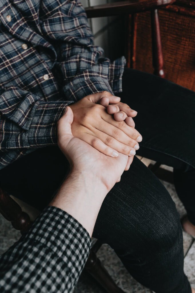 two people holding hands while sitting down two people holding hands while sitting down